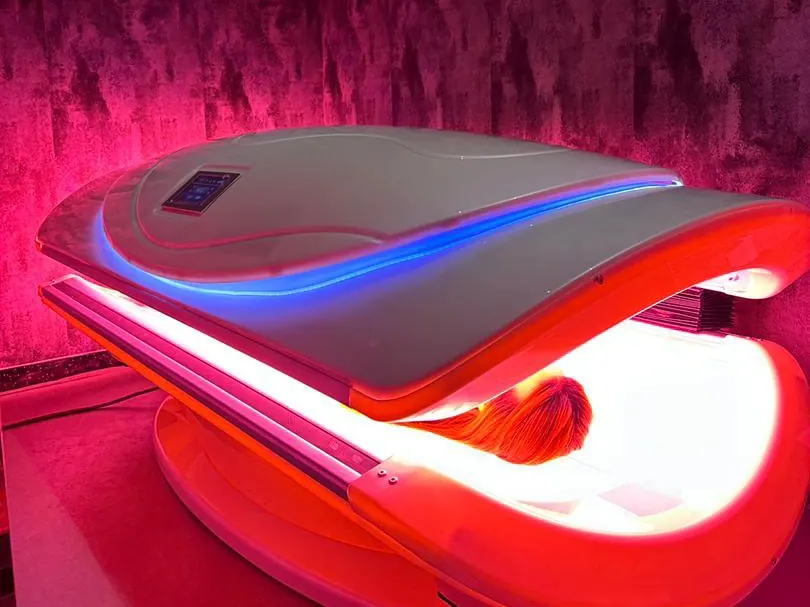 M6N dual-canopy red light therapy bed lit in a dark room